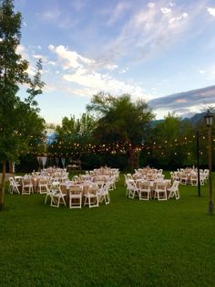 tables and chairs are set up in the grass for an outdoor wedding reception at dusk