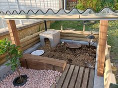 a small garden with rocks and gravel in the ground next to a wooden structure that has a potted plant on it