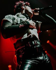 a woman in leather pants holding a microphone