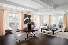 a living room filled with furniture and a table in front of a large window on top of a hard wood floor