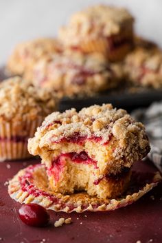 two muffins with cranberry filling on a red surface next to another muffin