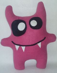 a pink stuffed animal with big eyes and teeth