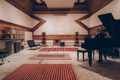 an empty room with a piano and several rugs