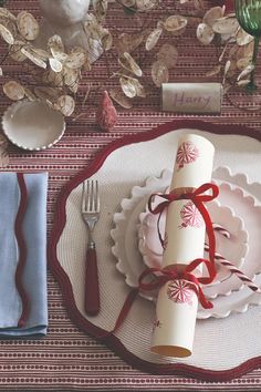 a place setting with napkins, silverware and red ribbon on the tablecloth