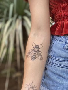 a woman's arm with a tattoo on it that has a bee on it