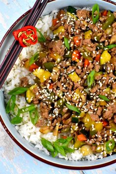 a bowl filled with rice, meat and veggies next to chopsticks