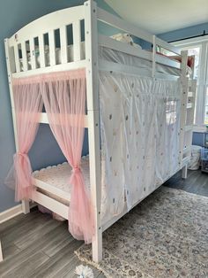 a child's bed with pink curtains on the top and bottom bunk, in a blue room