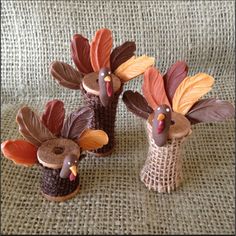 three turkeys made out of clay sitting on top of a cloth covered tablecloth