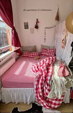 a bed with red and white checkered sheets in a room next to a window