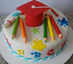 a cake decorated with crayons, pencils and a graduation cap on top