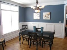 a dinning room with blue walls and white trim on the wall, wooden flooring