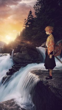 a man standing on top of a rock next to a waterfall