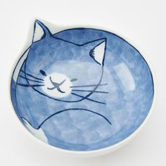 a blue and white bowl with a cat painted on it's face in front of a white background