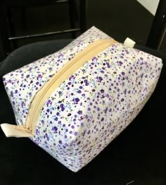 a purple and white flowered bag sitting on top of a black table