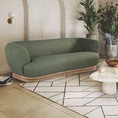 a living room filled with furniture and potted plants on top of a white rug