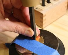 a person using a pair of scissors to cut a piece of blue tape on top of a machine