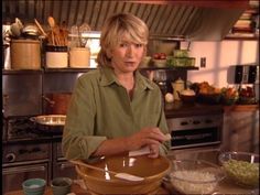 a woman standing in front of a kitchen counter with food on the bowl and utensils