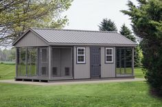 a small gray shed sitting on top of a lush green field