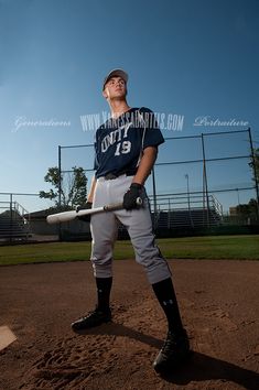 a baseball player is posing for a photo on the field with his bat in hand