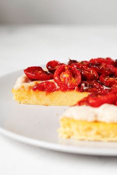 there is a piece of cake on the plate and it has red fruit on top