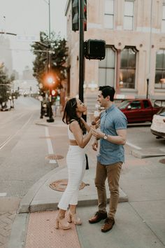 a man standing next to a woman on the side of a road near a traffic light