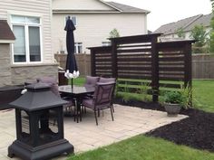 a patio with an umbrella and table in the middle of it, next to a fence