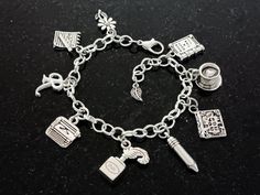 "This stylish charm bracelet has ten silver detailed charms, a typewriter, ink well & feather pen, pencil, \"Once Upon A Time' book, old-world style journal, 'memo' notebook pad with pen, cup of coffee/tea with heart, flower, leaf, and an initial for personalization. Gift for writer, author, journalist, blogger, secretary, teacher, or librarians birthday, holiday, anniversary, Mother's Day, retirement, or graduation. She will love your thoughtful gift. Gift from Spouse, Grandparent, Parent, Cowo Writers Aesthetic, Ink Well, Feather Pen, Script Initial, Heart Flower, Old World Style, Flower Leaf, Silver Charm Bracelet, Pen Pencil