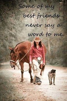 a woman walking her horse down a dirt road with a dog on the other side