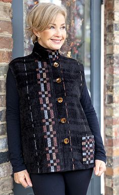 a woman standing next to a brick wall wearing a black jacket and leggings