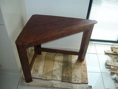 a wooden table sitting on top of a floor next to a pile of firewood