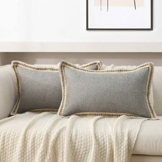 a couch with two pillows on top of it and a framed picture in the background