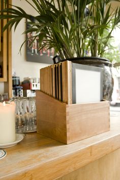 a wooden shelf with a candle and some plants on it in a home office setting