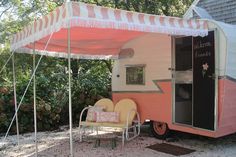 an orange and white trailer parked in front of a house with a canopy over it