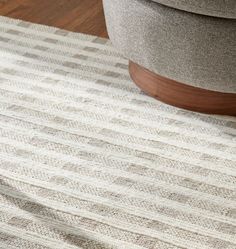 a close up of a rug on the floor with a chair and ottoman in the background