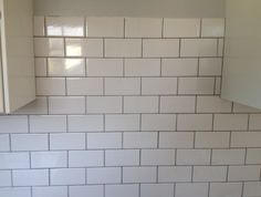 a kitchen with white subway tile on the backsplash and cupboards in the corner