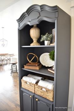 a black bookcase with baskets on top of it