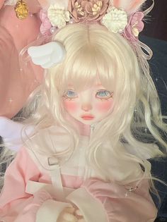 a close up of a doll with blonde hair and flowers on her head, wearing a pink dress