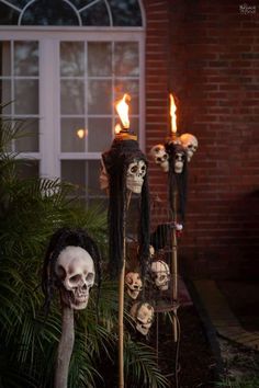 halloween decorations in front of a house with candles and skulls on the outside, including fake heads