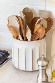 wooden spoons and spatulas in a white ceramic container on a kitchen counter