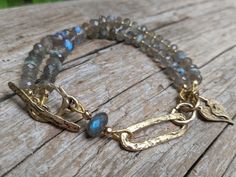 a close up of a bracelet on top of a wooden table with beads and chains