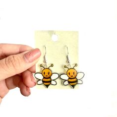 a pair of earrings with a bee design on the front and back of each ear