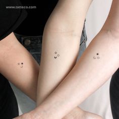 two people with matching tattoos on their arms, both holding each other's hands