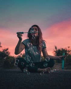 a woman sitting on the ground blowing bubbles in front of her face and holding a toothbrush