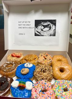 a box filled with lots of different kinds of doughnuts on top of a table