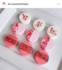 four pink and white buttons sitting on top of a white plate next to each other