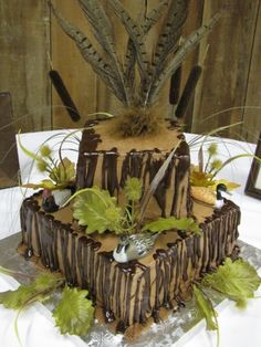 a three tiered chocolate cake decorated with leaves and feathers