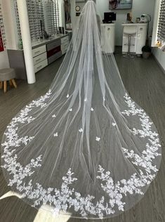 a wedding veil with white flowers on the bottom is hanging in front of a mirror