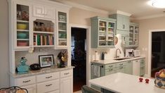 a kitchen filled with lots of white counter tops and cupboards next to a dining room table