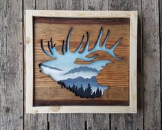 a wooden frame with a deer head and mountains on it