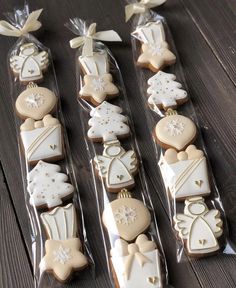 some cookies are in plastic bags on a wooden table and one is decorated with icing